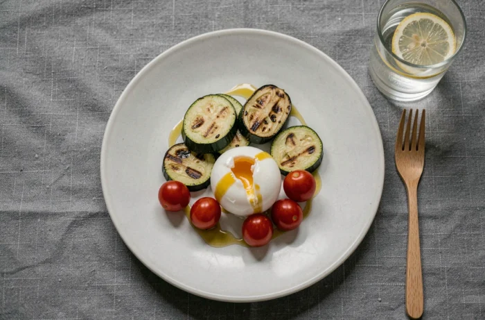 Assiette équilibrée pour le dîner en chrononutrition vue de dessus avec courgettes rôties, œuf mollet et tomates cerises